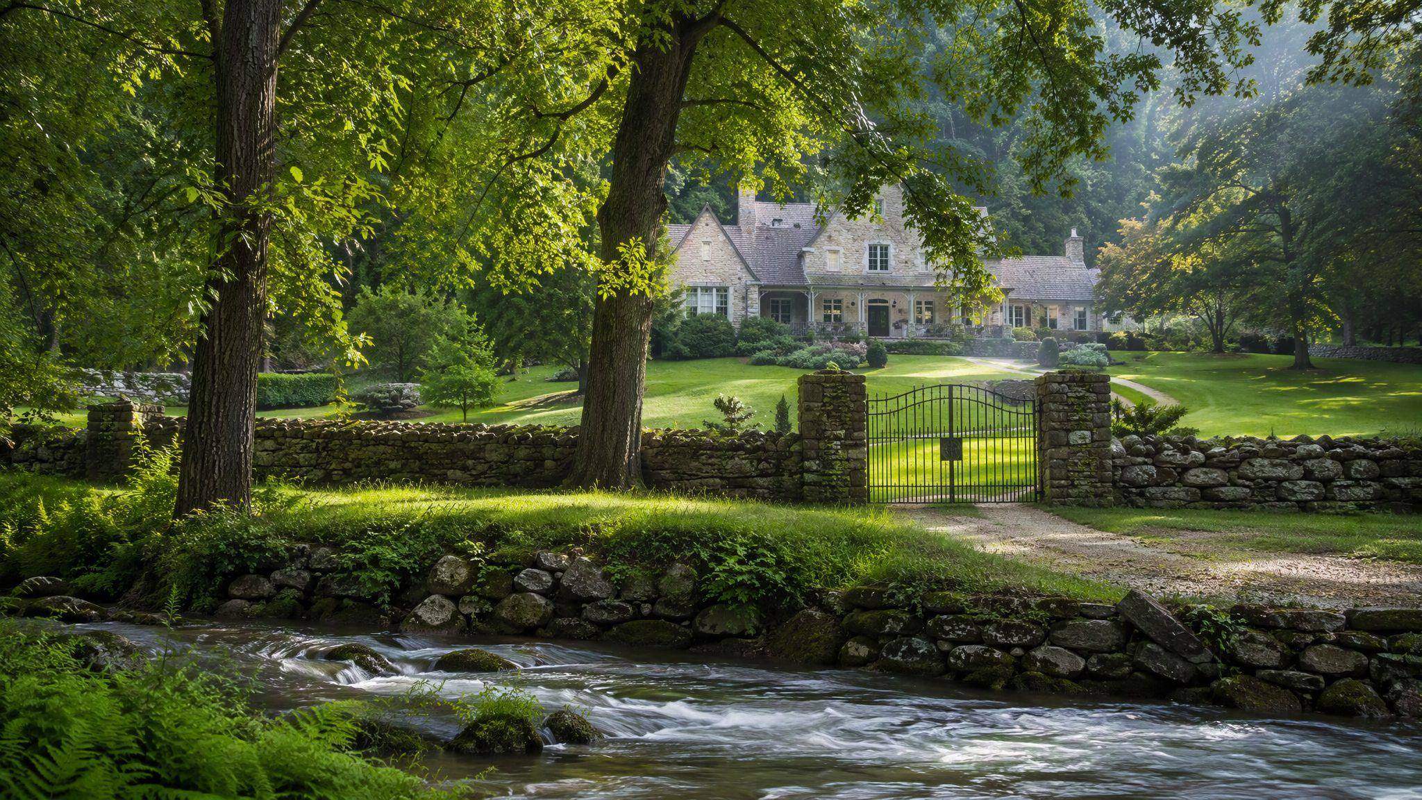 Historic white farmhouse and stone wall along a creek in Elm Springs, Arkansas