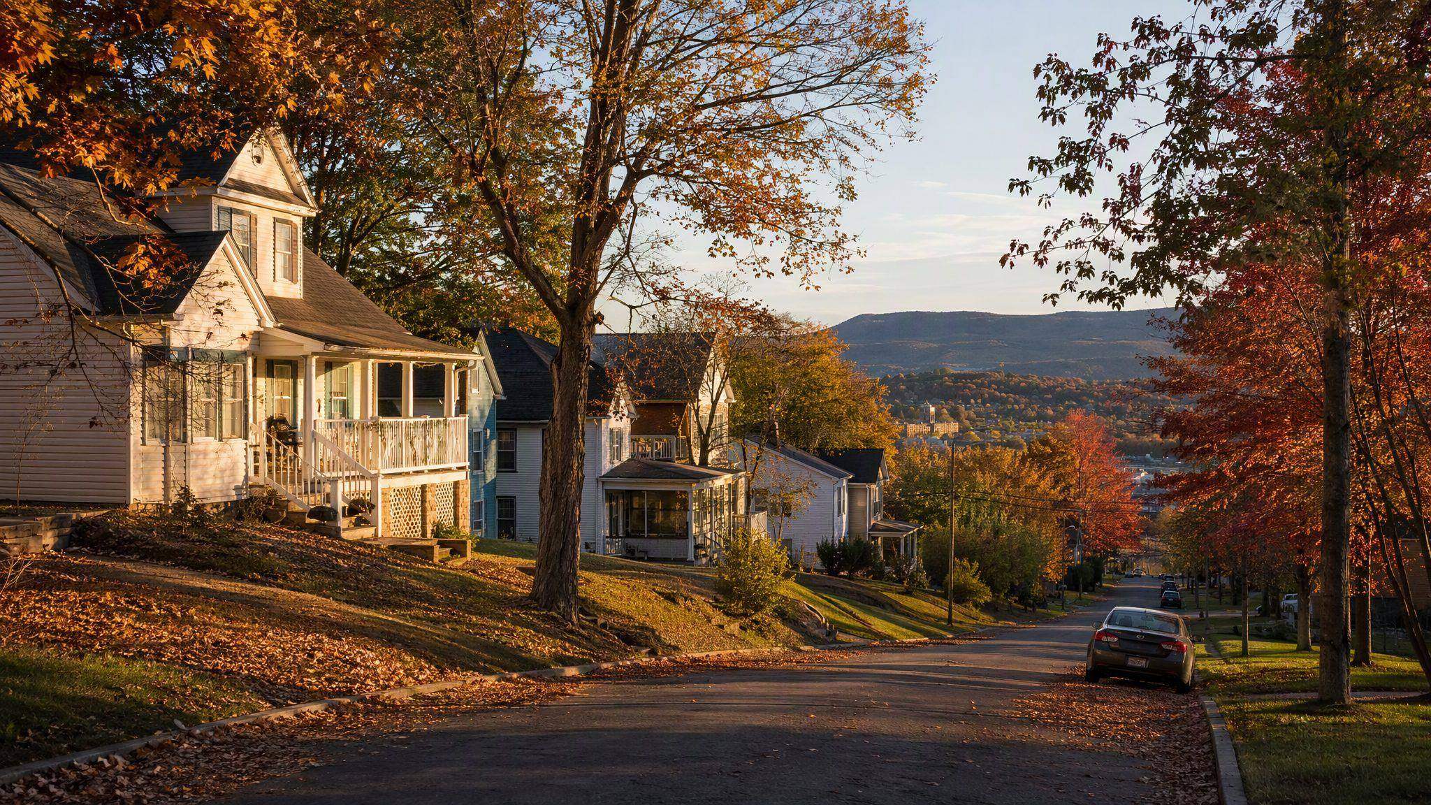 Historic homes on a tree-lined Fayetteville street in autumn with Ozark hills beyond